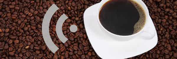 A cup of black coffee in a white cup on a white saucer sitting on a roasted coffee beans with RSS feed symbol in grey next to the cup
